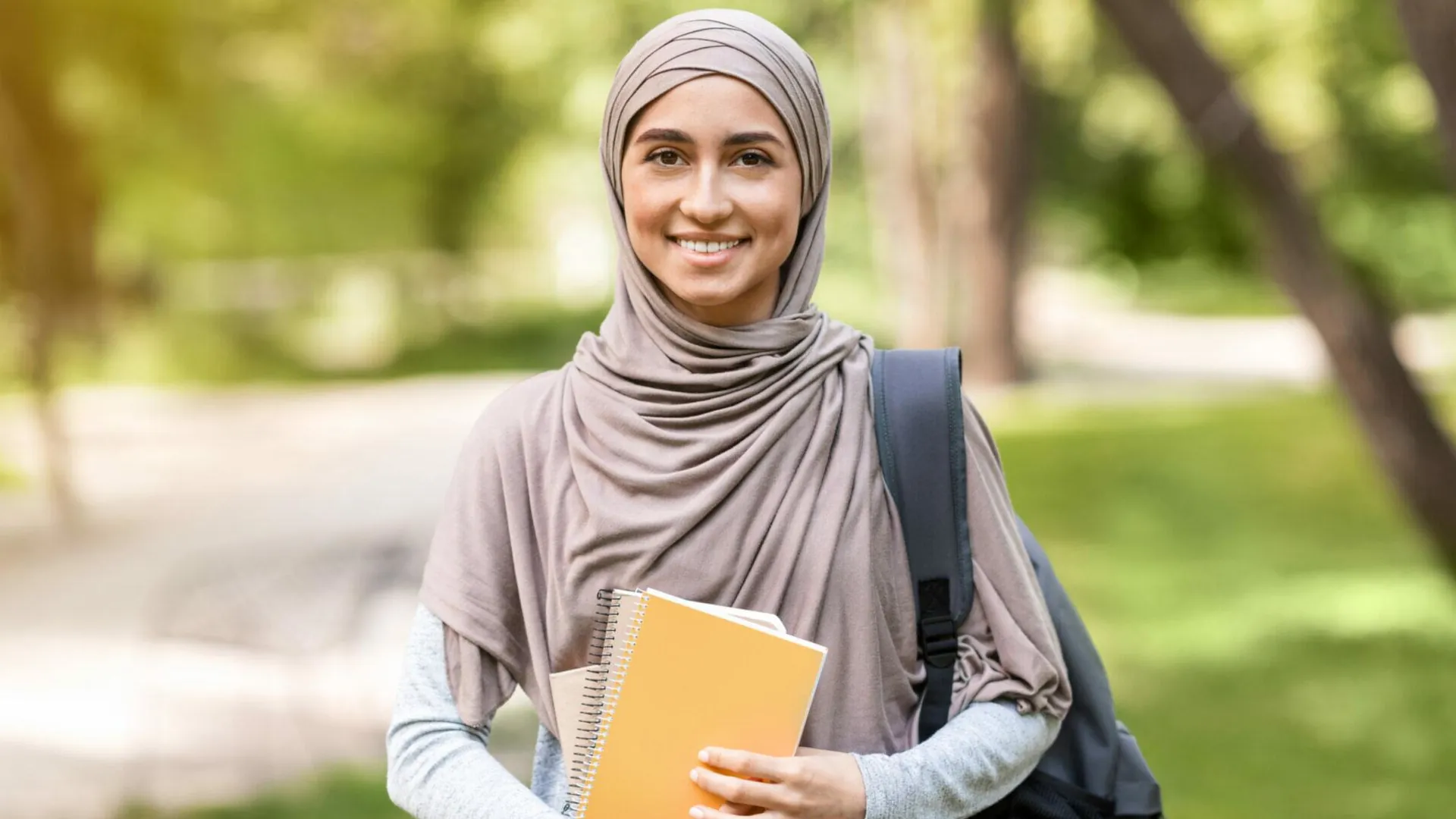 Une jeune musulmane tenant des cahiers d'école et un sac à dos