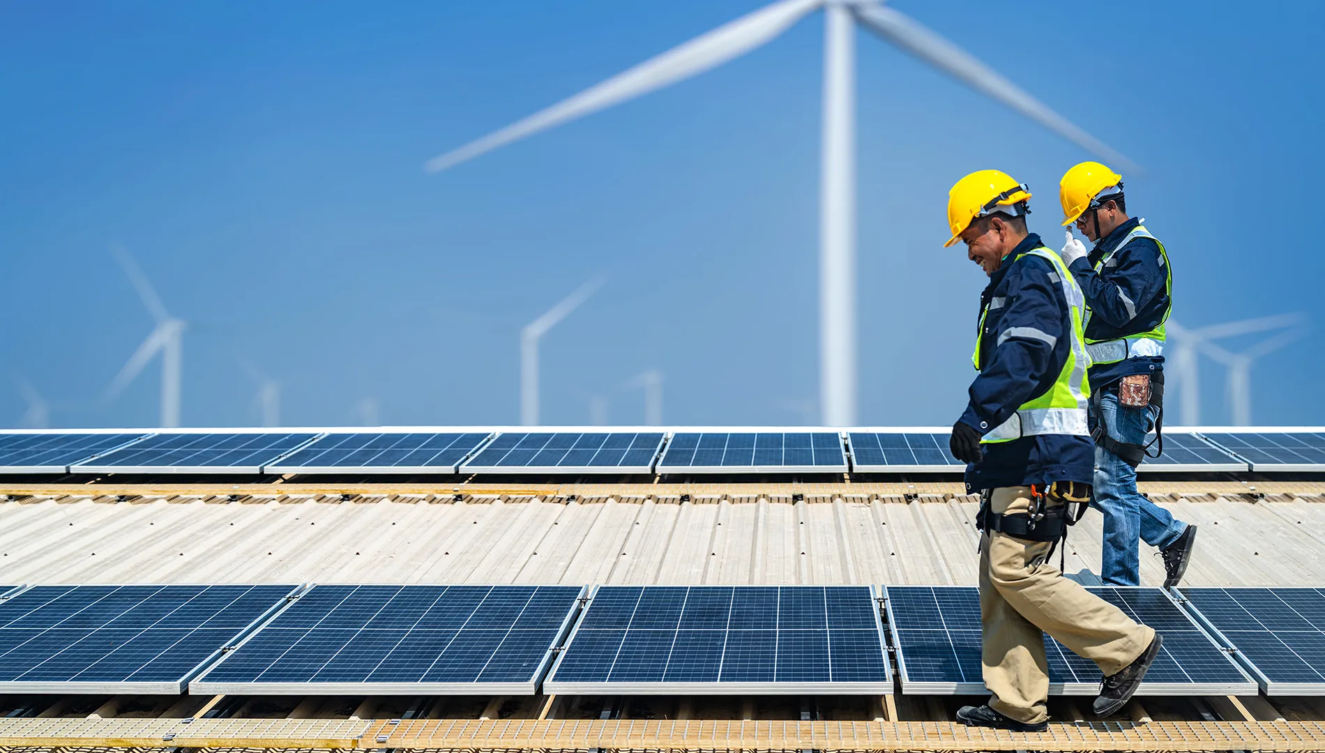 Deux techniciens éoliens sur le toit d'un édifice avec des panneaux solaires