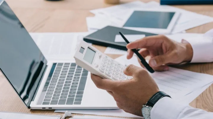 Vue de près d'un clavier d'ordinateur portable et calculatrice avec une main prête à taper
