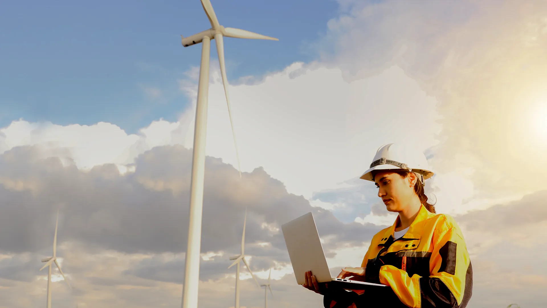 Une technicienne en maintenance éolienne qui prend des mesures proche d'une éolienne