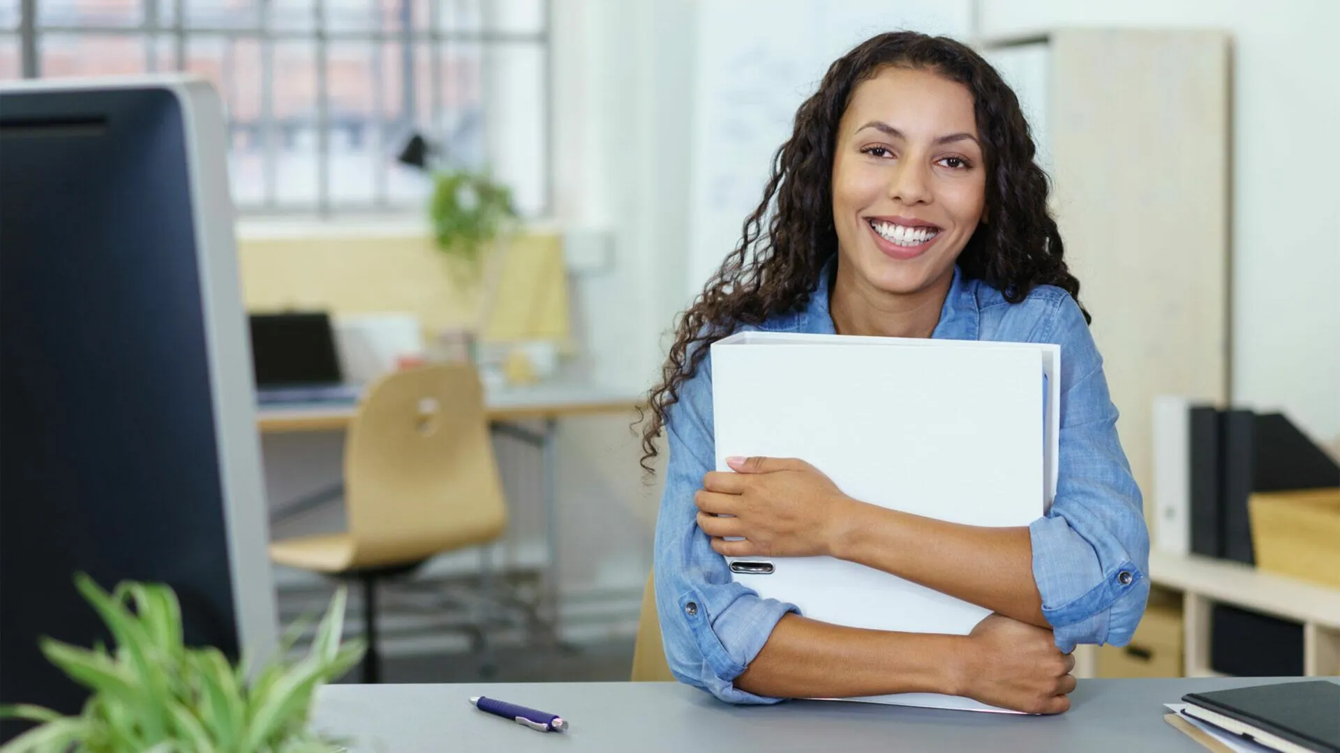 Une adjointe administrative qui sourit derrière son bureau