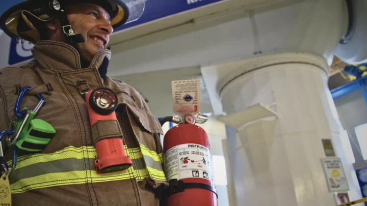 Pompier en uniforme tenant un extincteur dans une éolienne